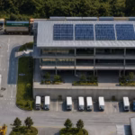 Modern logistics and warehouse facility with rooftop solar panels and freight transport infrastructure.